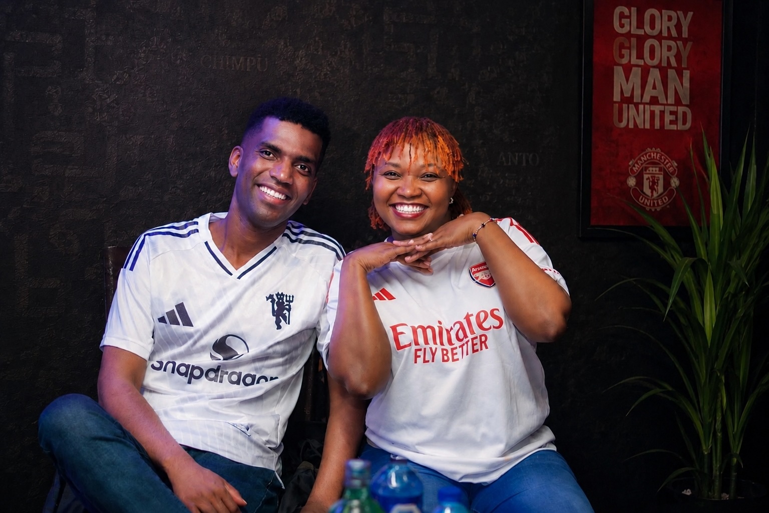 Steve in a Manchester United jersey and Shee in an Arsenal jersey, smiling